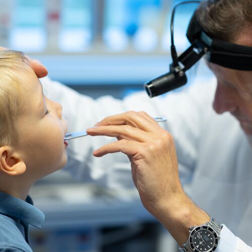 Kleiner Junge wird von Dr. Lübben im Mund/Hals untersucht